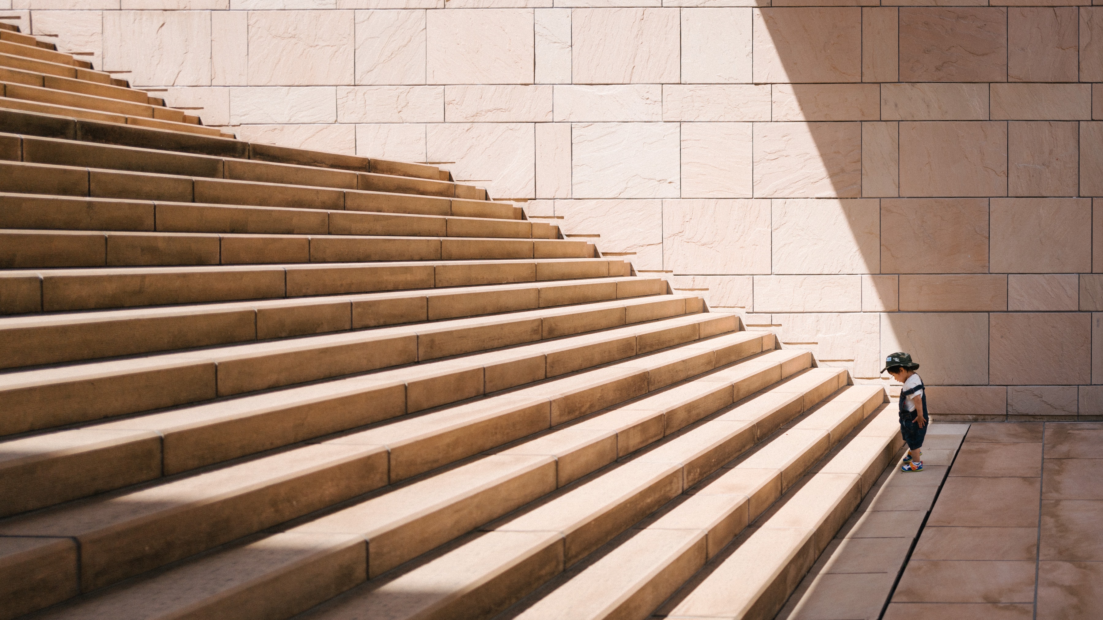 Child at the foot of a long staircase, staring at the first step